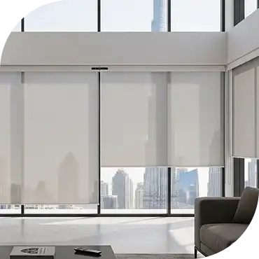 Interior view of a modern living room with large floor-to-ceiling windows fitted with light beige roller blinds, overlooking the Dubai skyline.